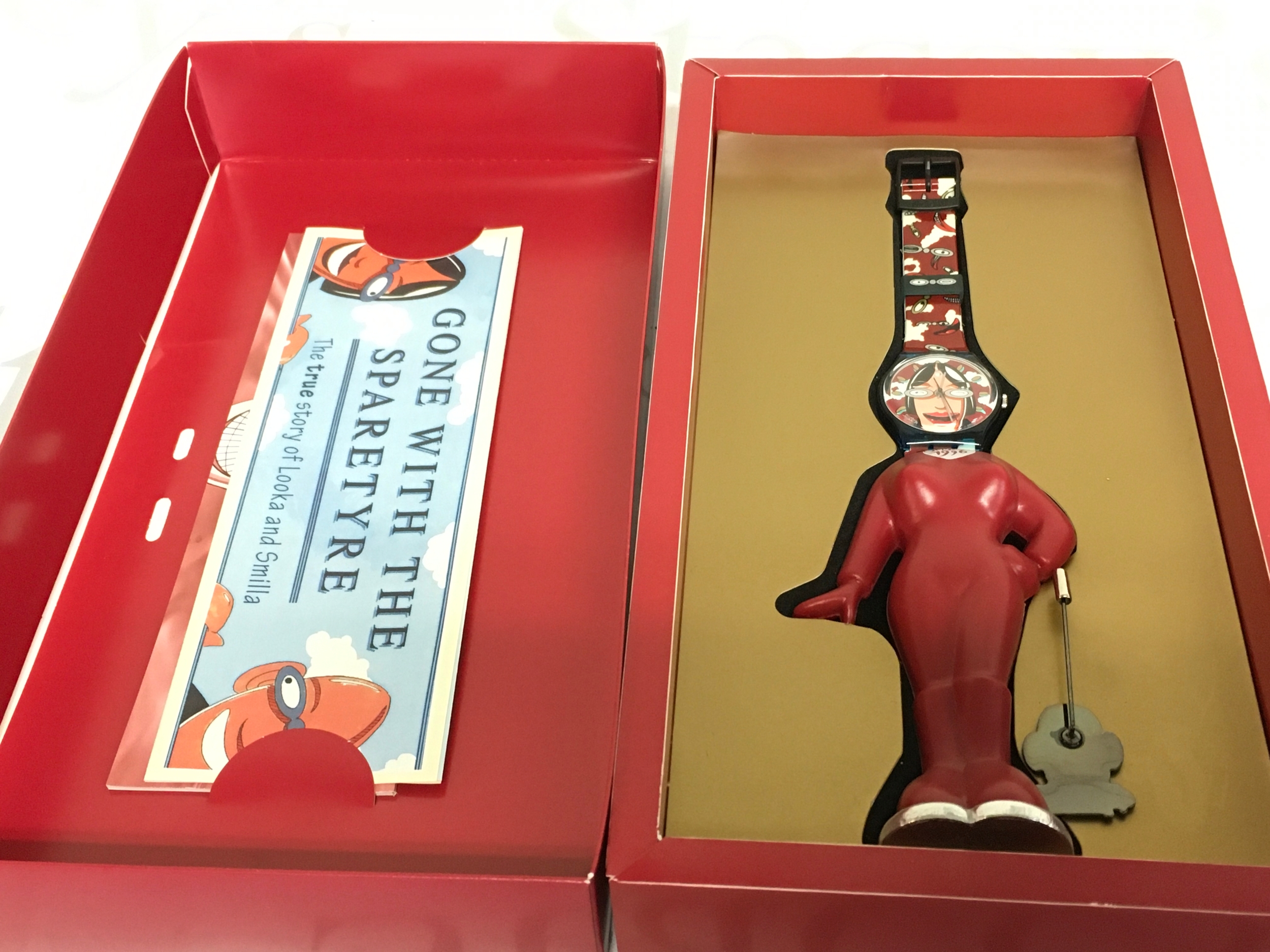 1996 Swatch Gent Club Special named "SMILLA" (model GZ701) designed by Stefano Pirovano. The set includes the wristwatch, a unique red character-shaped stand, and a matching lapel pin.