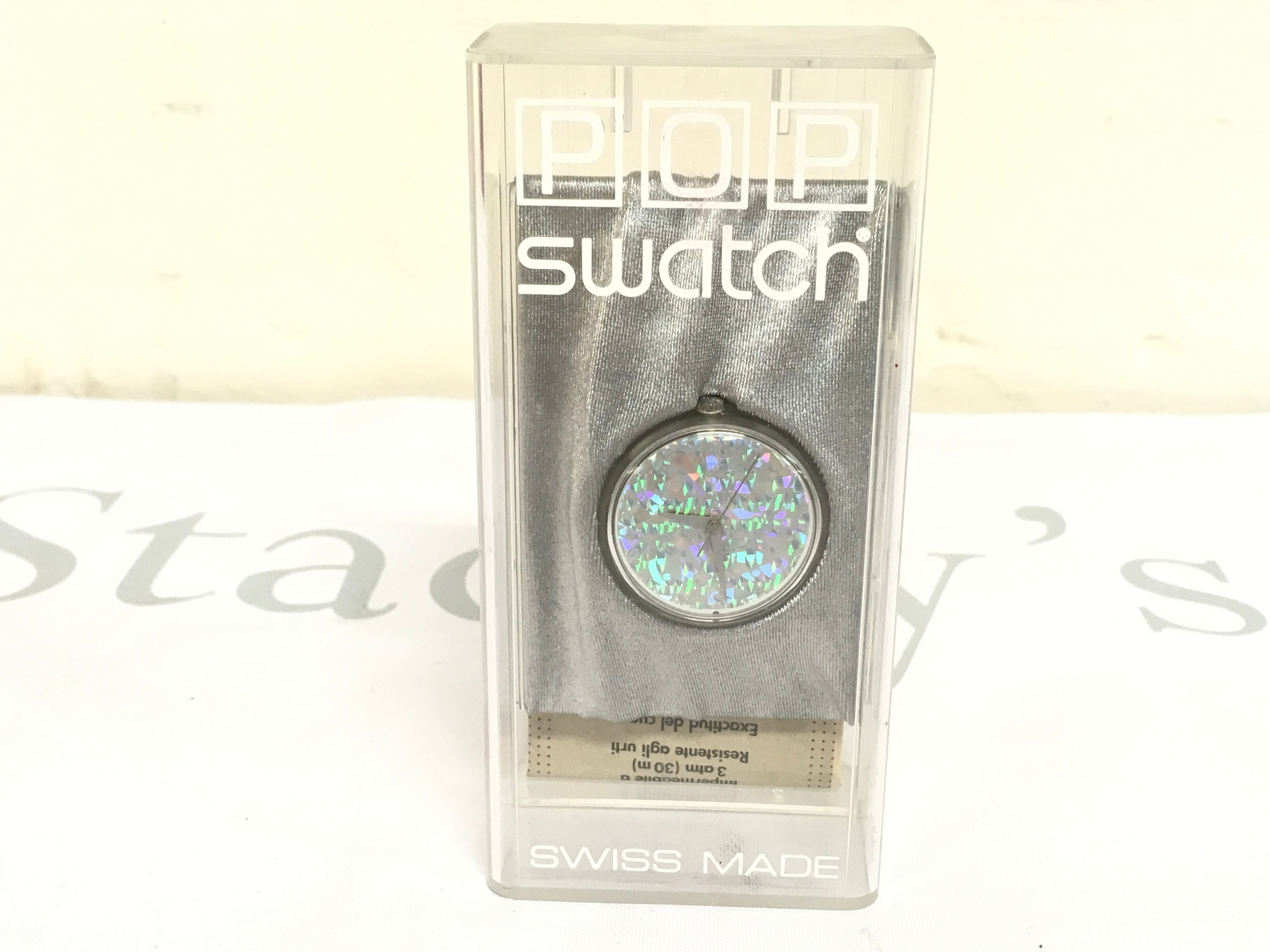 Swatch Pop watch, likely from the 1990s, in its original clear plastic packaging. The watch features a distinctive silver-colored, mirrored or sparkling dial with a holographic effect