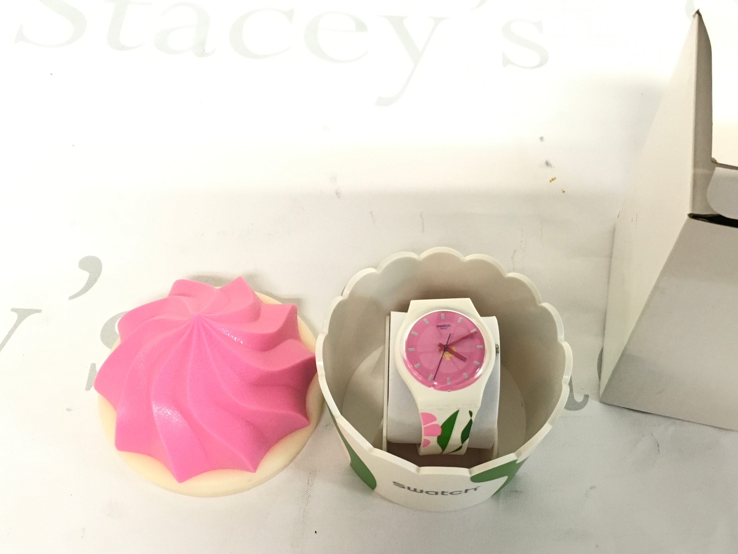 Swatch PRIMEVERE (GZ304) watch featuring a pink floral dial and white strap packaged inside a special cupcake-shaped box.