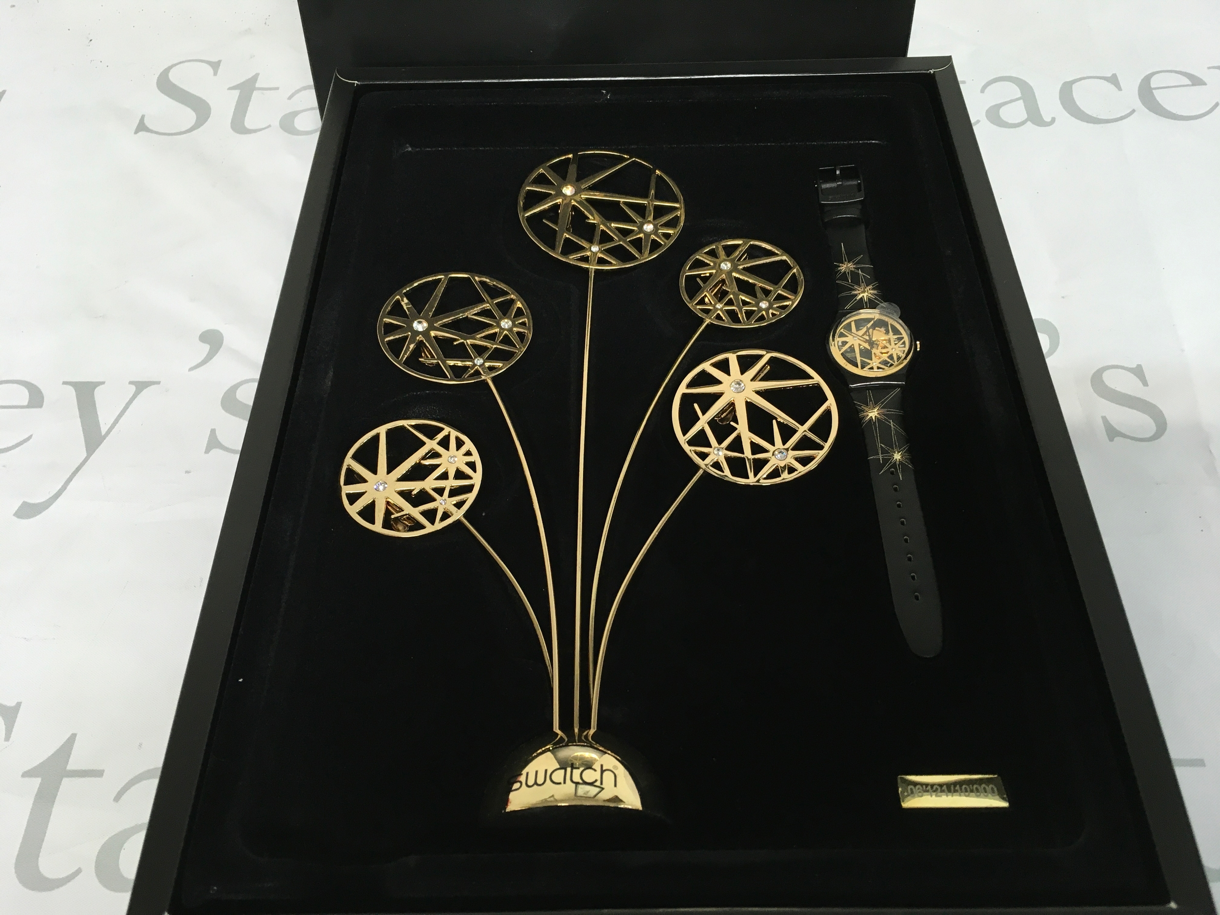 Swatch "Star Edition" GZ199S limited edition Christmas special from 2009. It features a black strap watch with gold star details packaged with a matching gold-colored star-themed sculpture. The set is a limited release of 10,000 pieces.