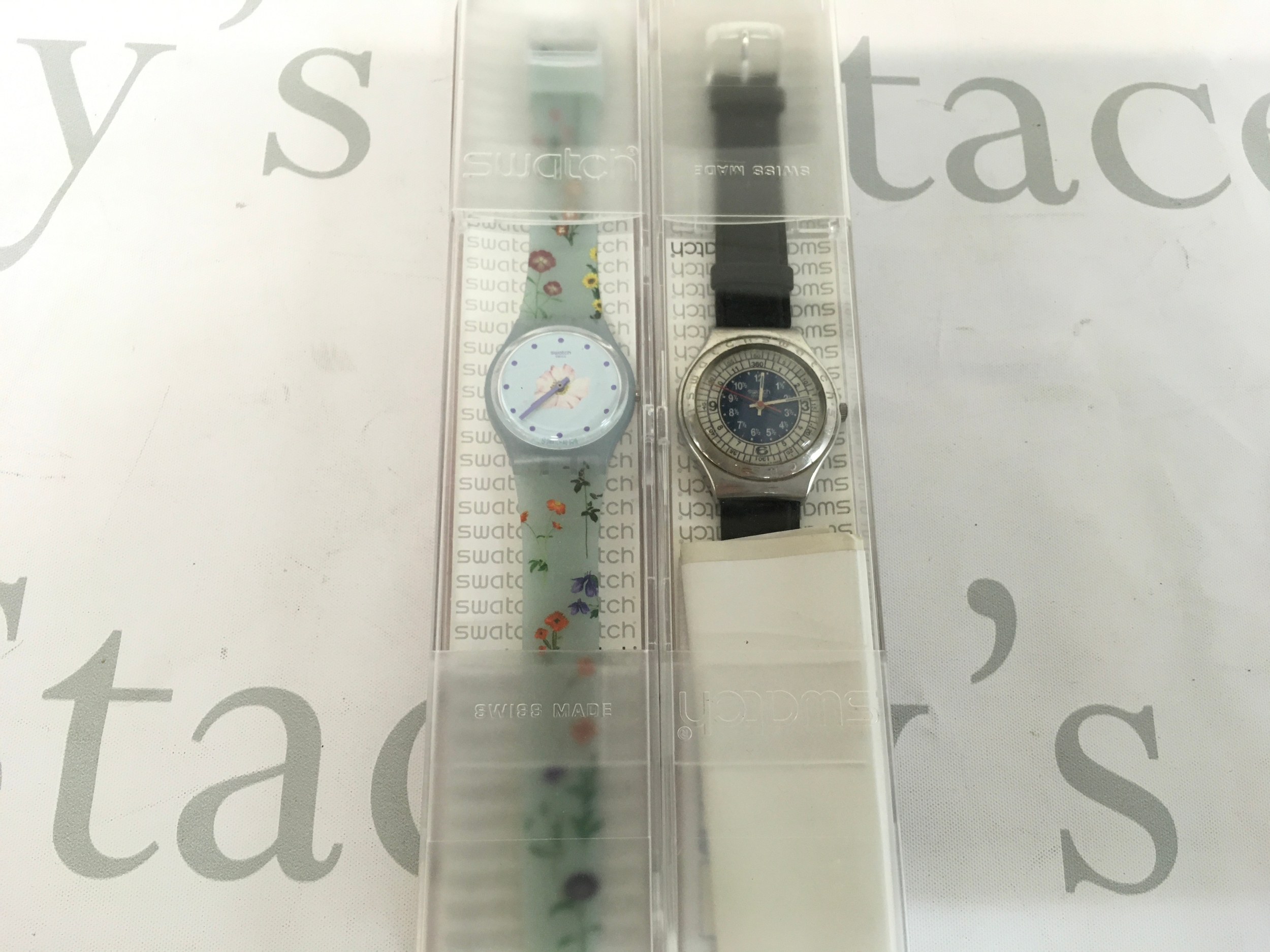 Swatch Pistillo (GS152) features a light blue floral dial and a matching transparent silicone strap and vintage 1993 or 1994 Swatch Irony "Ocean Storm" (model YGS103) featuring a dark blue dial with a complex inner scale and a stainless steel case