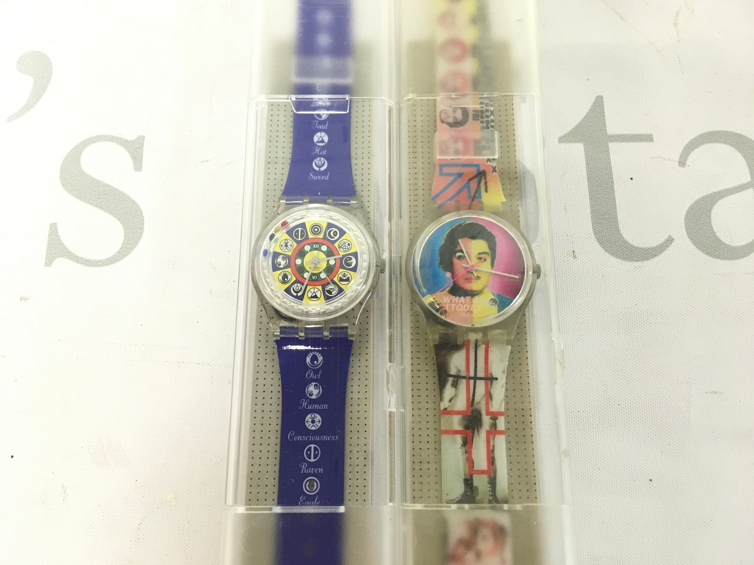 two collectible Swatch Gent watches, including the 1996 "Oracolo" GZ151 designed by Walter Wegmüller, which showcases a tarot-inspired dial