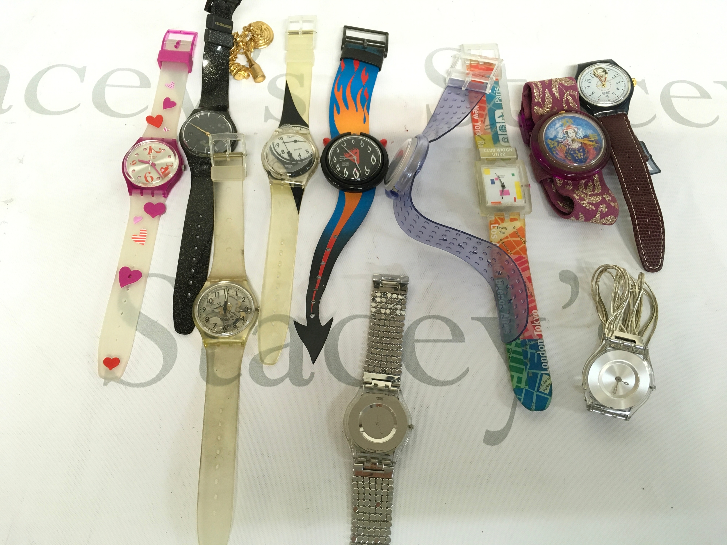 collection features vintage Swatch wristwatches from the 1990s, often sought after by collectors. The watches showcase diverse, artistic designs including heart patterns, flame motifs, and city-themed graphics.  