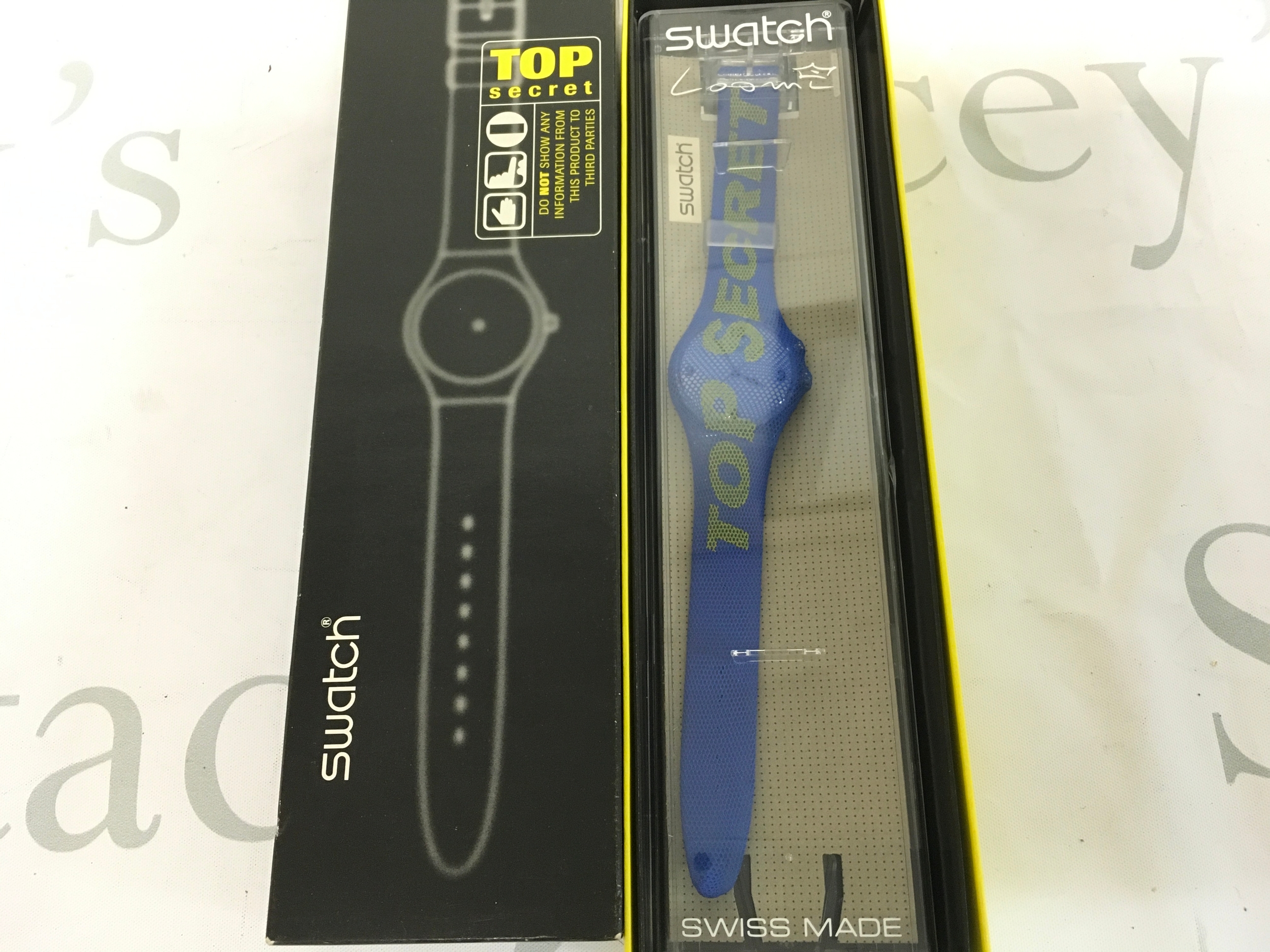 1998 Swatch "Top Secret" Loomi (model GK905)wristwatch, featuring a blue strap with "TOP SECRET" text in yellow. It comes in special packaging as part of a club release.