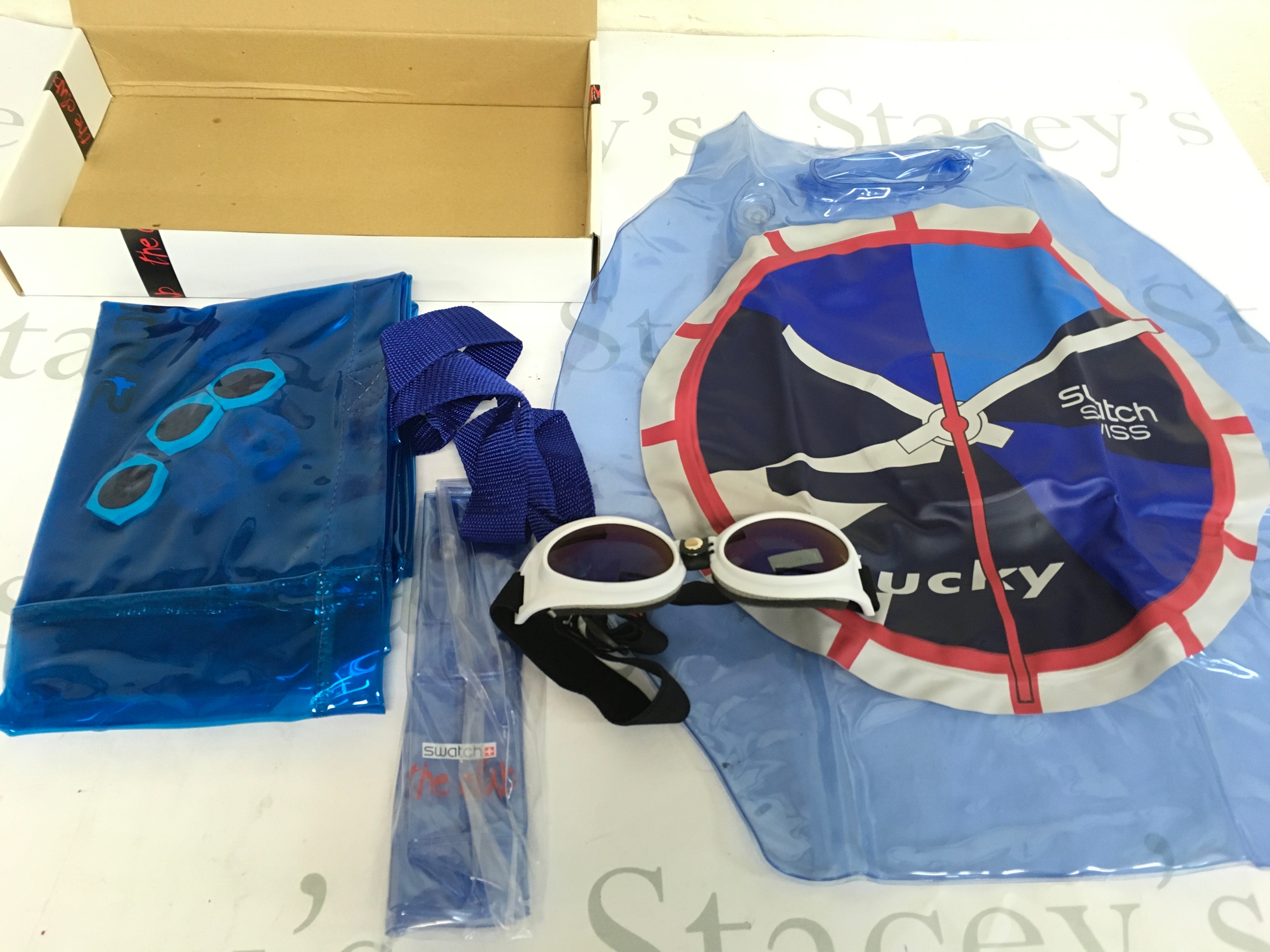 Swatch collectables including an inflatable beach bag, modular Swatch Eyes sunglasses/goggles, and a strap pouch.