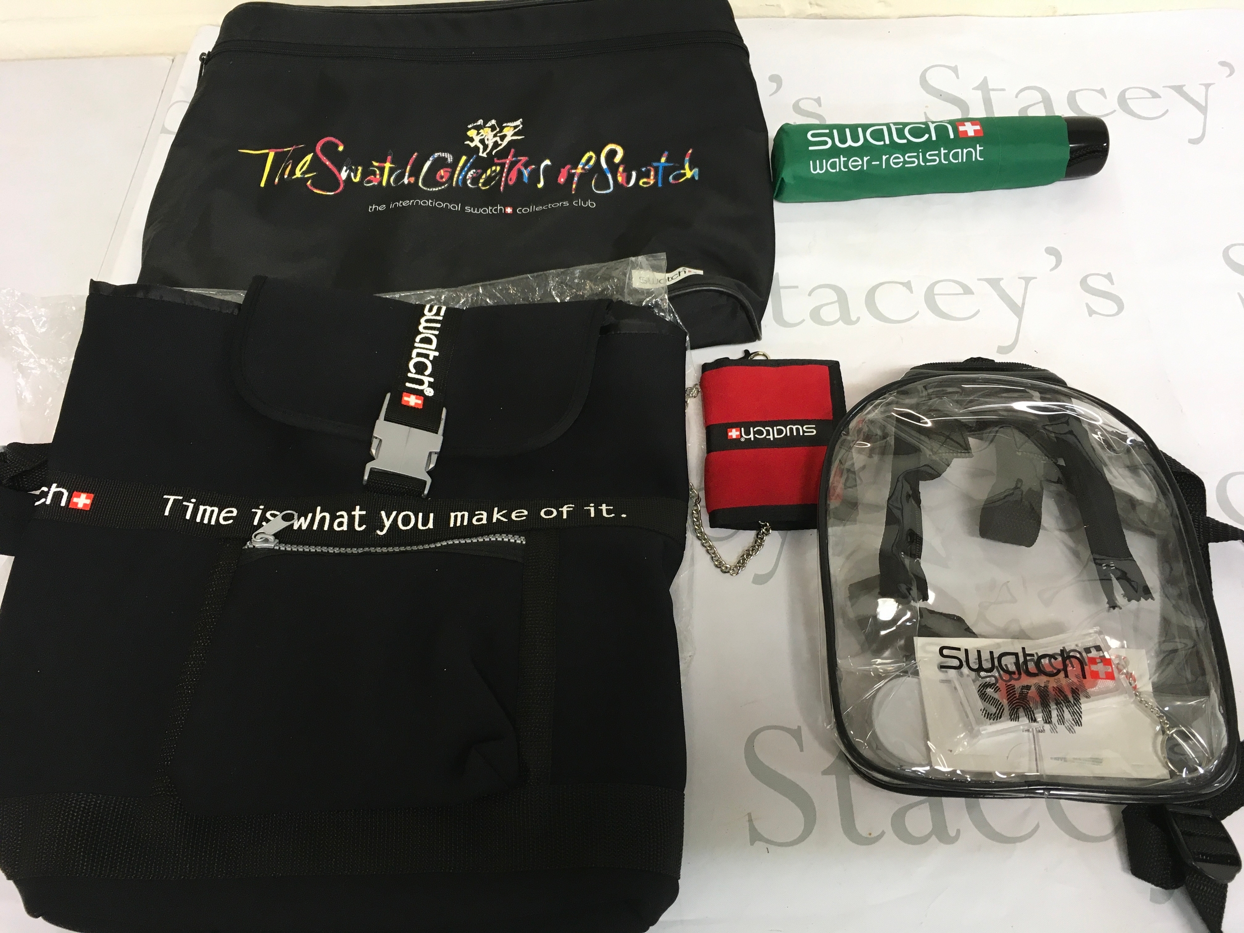 collection features various Swatch branded accessories, including a "Collectors of Swatch" tote bag and a clear plastic skin backpack with condom breath mints etc