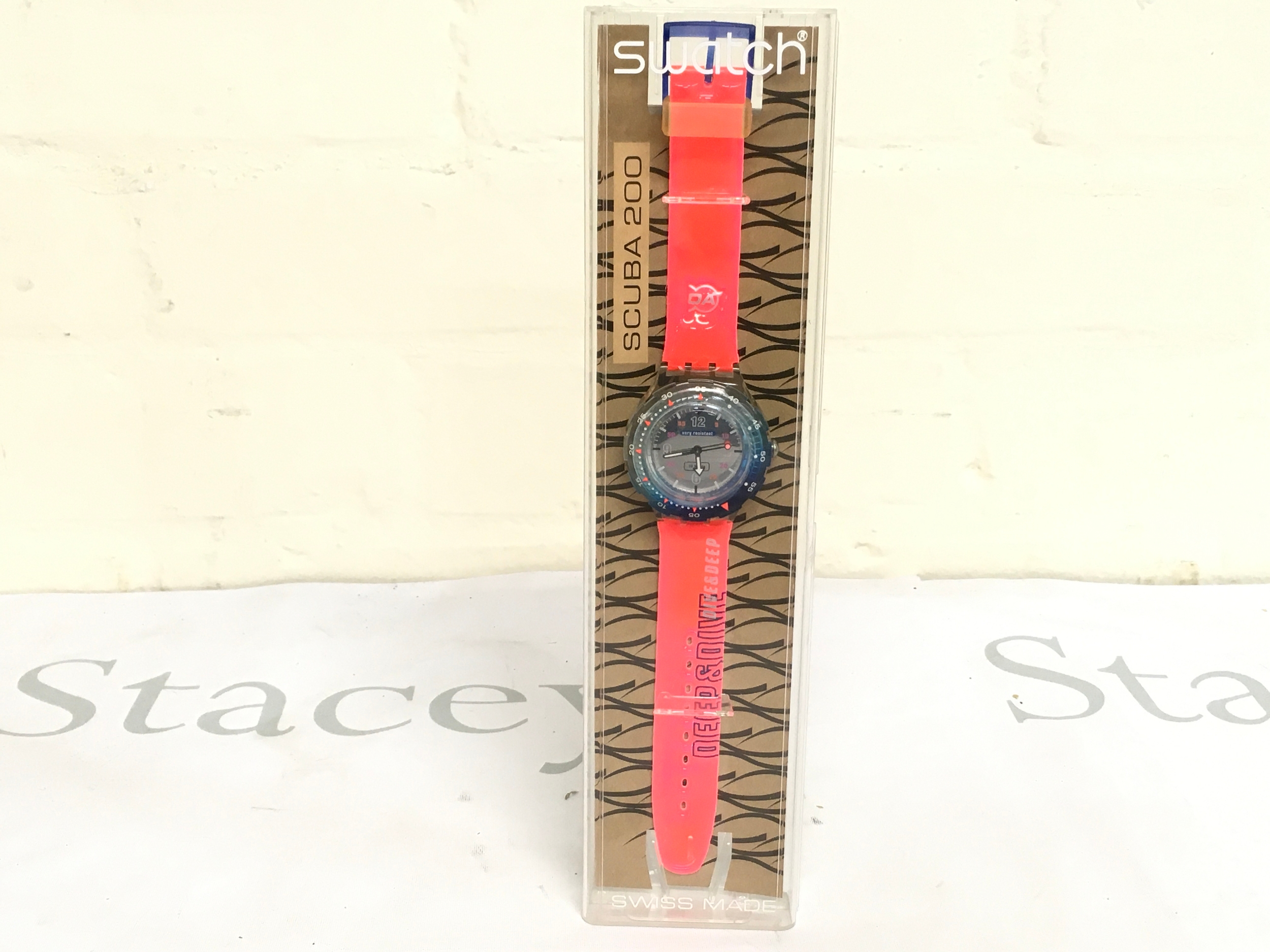 1999 Swatch Scuba 200 "Deep and Dive" (SDK134) watch. It features a 38 mm case diameter and is water-resistant up to 200 meters (656 feet). The watch comes with its original packaging and has a bright orange strap with "DEEP & DIVE" branding