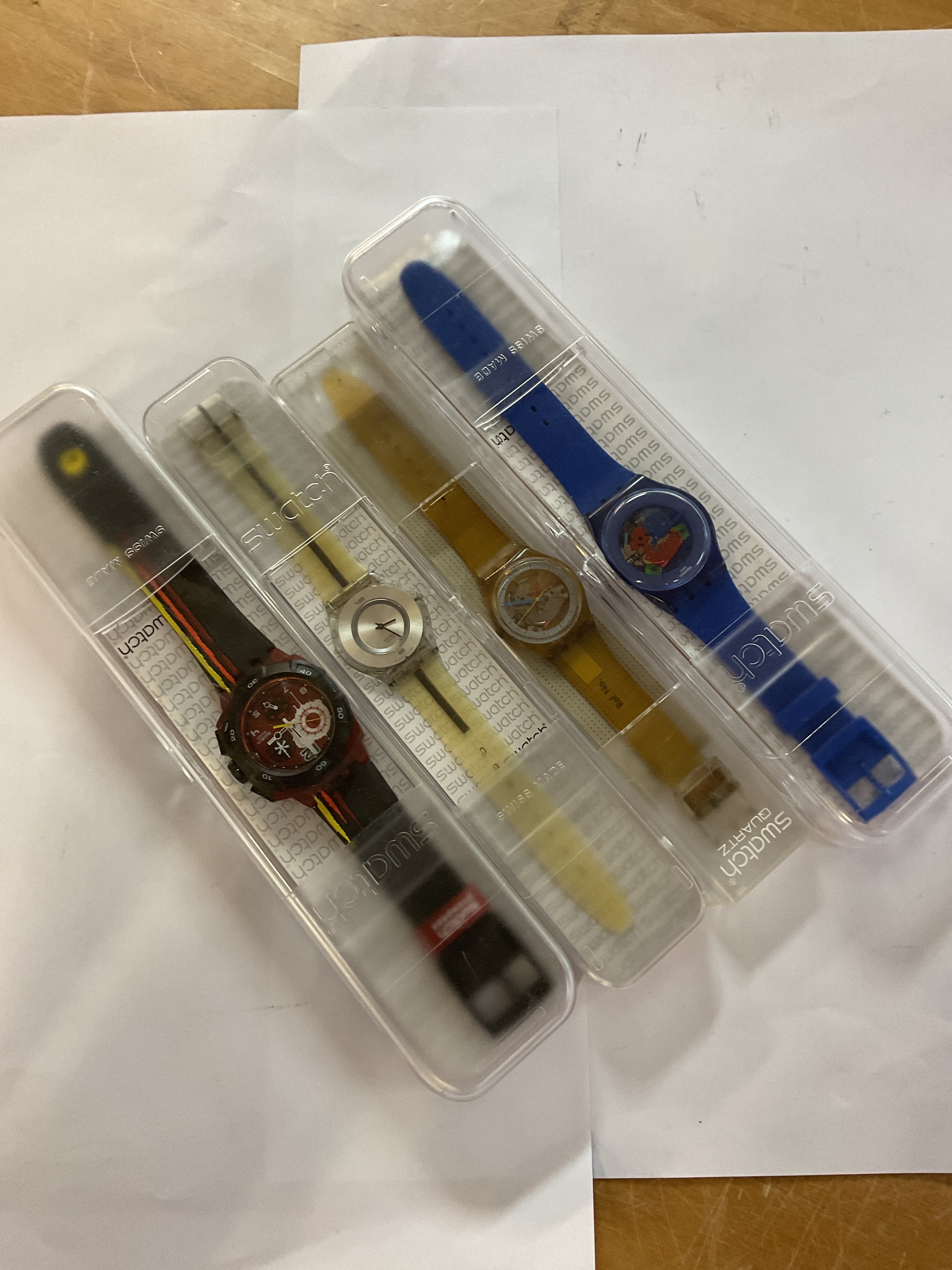 Four cased Swatch watches.