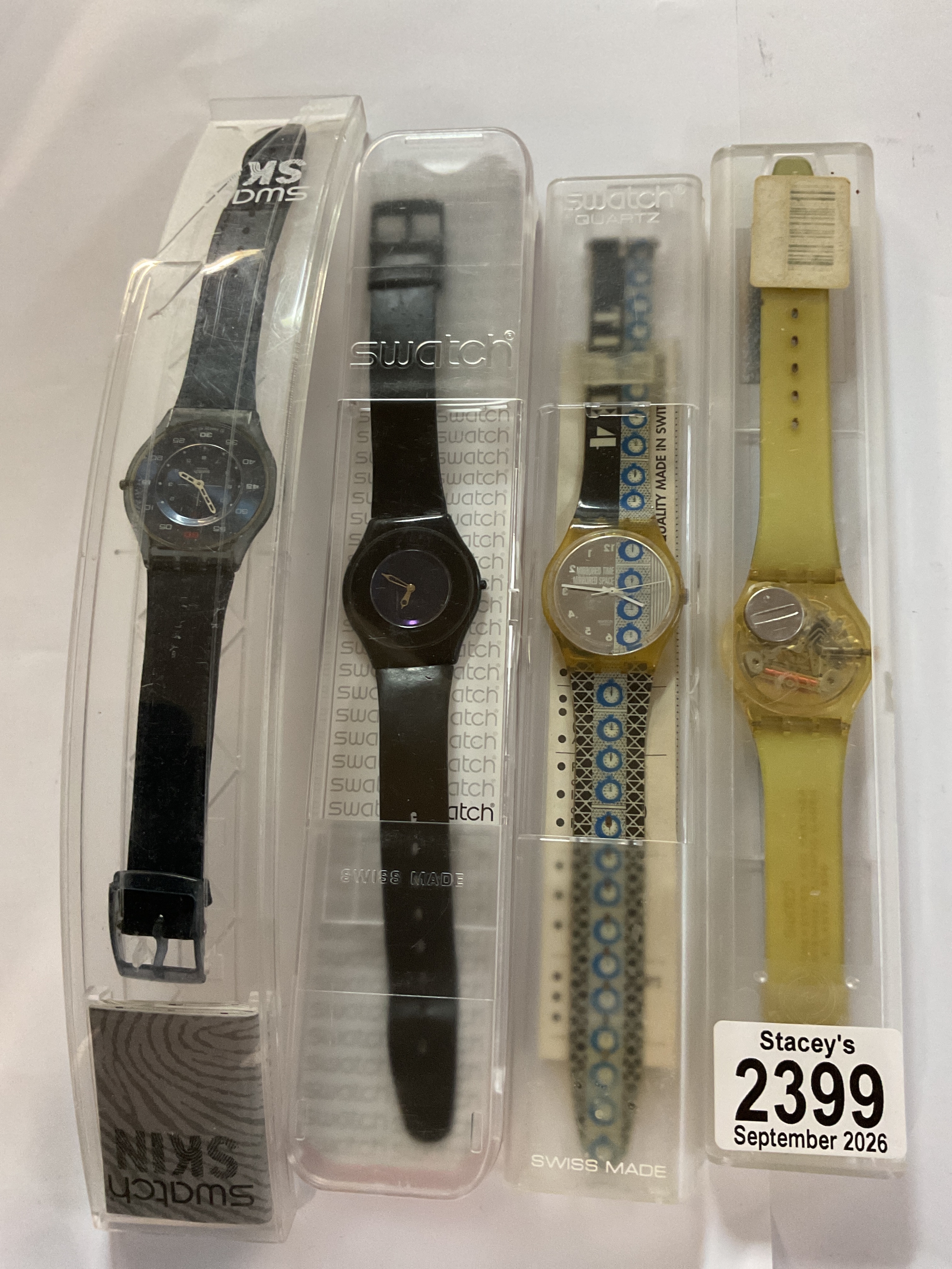 Four cased Swatch watches.