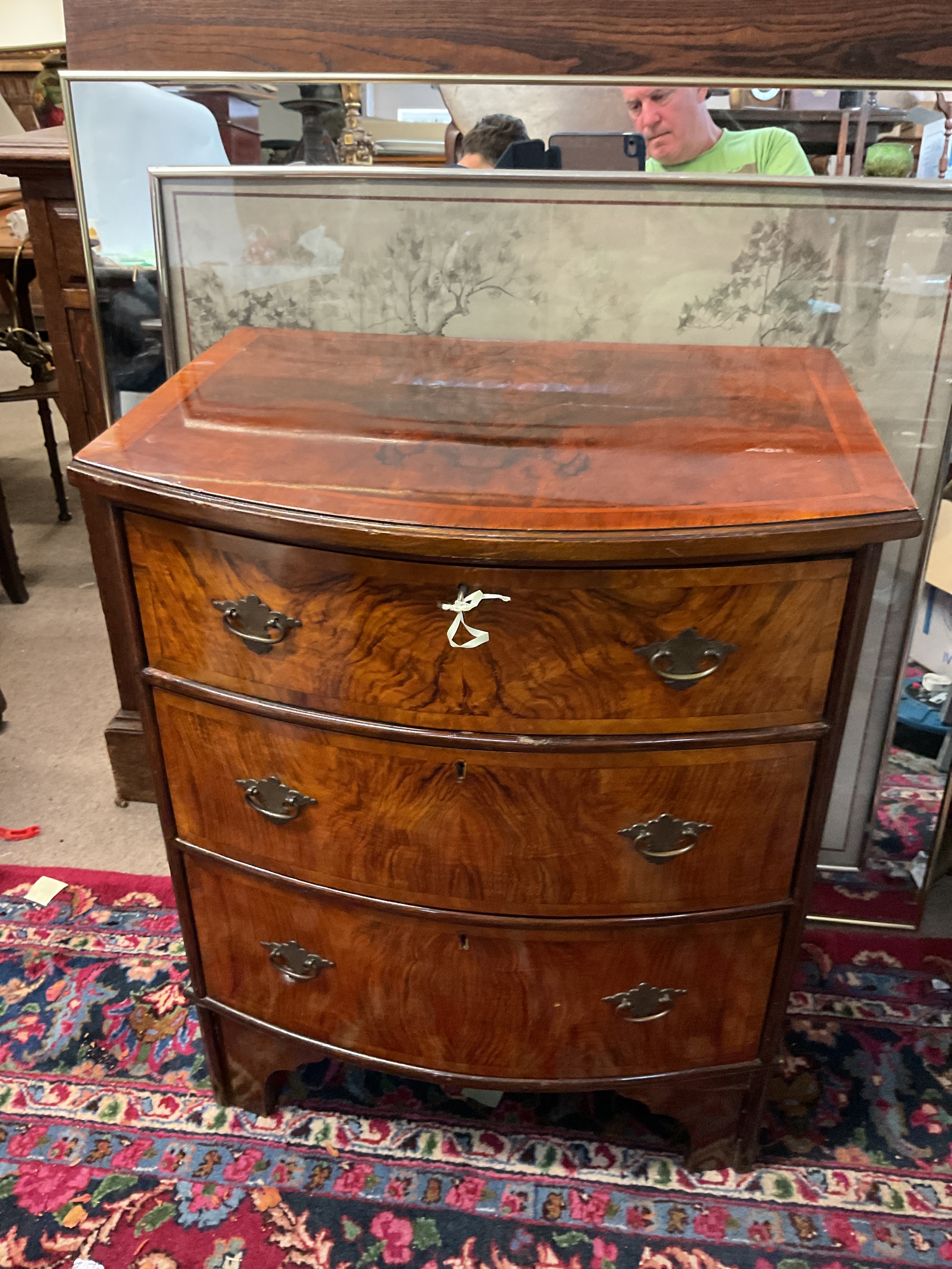Flame Mahogany veneered three drawer bow fronted set of drawers, on bracket feet and with key, c1900 in Georgian style. 74 cm x 60 cm x 36 cm.