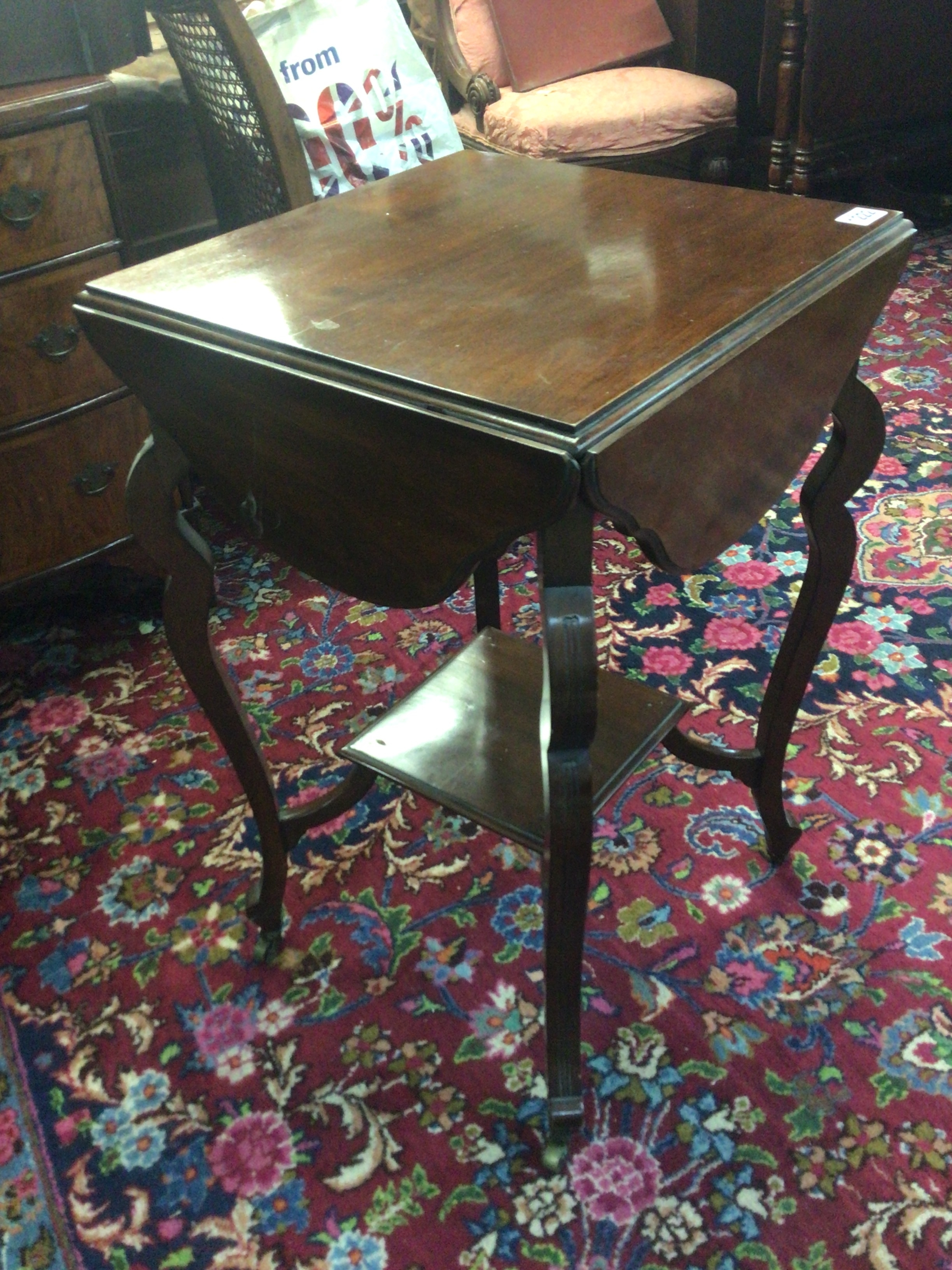  An Edwardian walnut occasional table with a shaped top with four hinged leaves on cabriole legs. 
