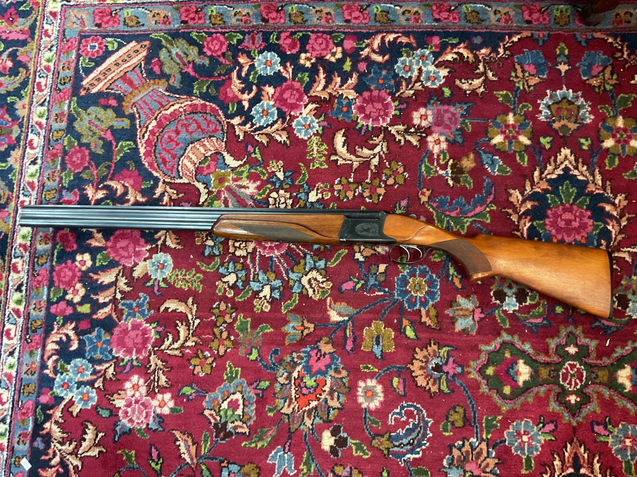 SHOTGUN LICENSE REQUIRED ON THIS LOT AS WELL AS ARRANGING APPOINTMENT TO VIEW AND COLLECT THANK YOU. A12 gauge Baikal over and under shotgun, 27.5 cm barrels, Ser No H02133. With engravings to plates and a pair of snap caps.clean barrels.