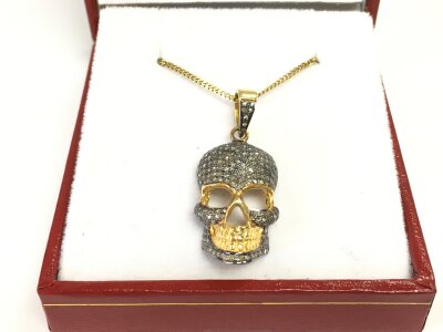 Diamond encrusted silver gilt skull pendant on a gold plated silver chain.