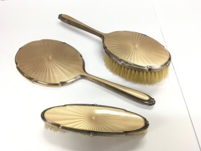 A three piece silver and guilloche enamel backed dressing table set.