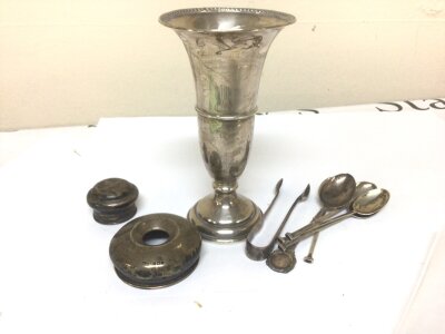 A Silver vase with loaded base a quantity of silver spoons and silver tidy jar lids.