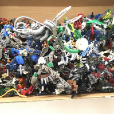 Box containing a collection of loose Lego Bionicle figures.