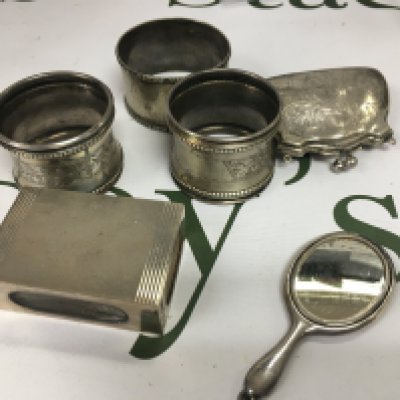 A small silver purse, silver napkin rings, a miniature mirror and a natch box case.