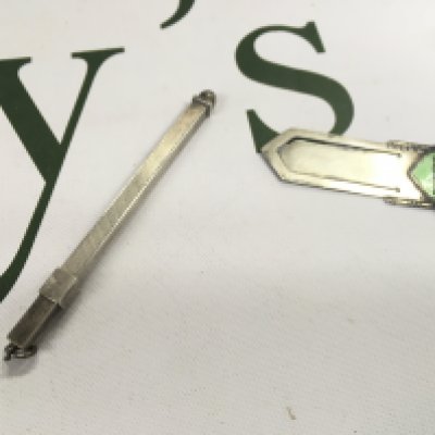 A silver enamel clip with a silver cocktail stirrer.