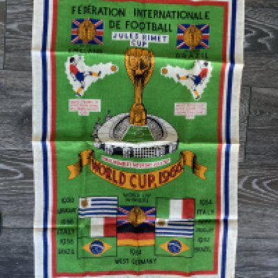 1966 Football World Cup Linen Tea Towel: Stunning unused large colourful tea towel with the World Cup logo plus names and flags of previous winners. Jules Rimet pictured above Wembley with date of the final below. Measures 31 x 20 inches.