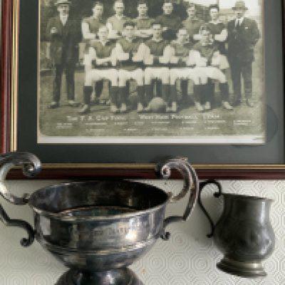 Billy Moore West Ham Football Cups: Crawley Charity Cup in aid of the East Ham Memorial Hospital, year unknown and very blemished. C/W a much smaller tankard engraved to WGB Moore from Mr + Mrs Cowen. Not sure if these were from his playing days or coaching so a span of 40 years 1920 to 1960 a possibility. Framed replica photo of the 1923 Cup Final team featuring Moore. These came with his medals that feature at the beginning of the catalogue.