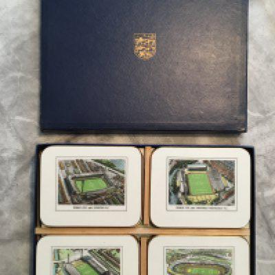1966 World Cup Set Of Placemats + Coasters: 8 unused coasters and 8 unused place mats each depicting a football ground used in the World Cup. In original box with 3 Lions to front and spacers for the coasters. Unusual to see gold edging like new and baize to rear in perfect condition.