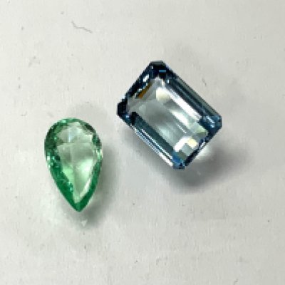 A loose emerald cut aquamarine 0.84g together with a loose pear shaped emerald 0.28g. (A)