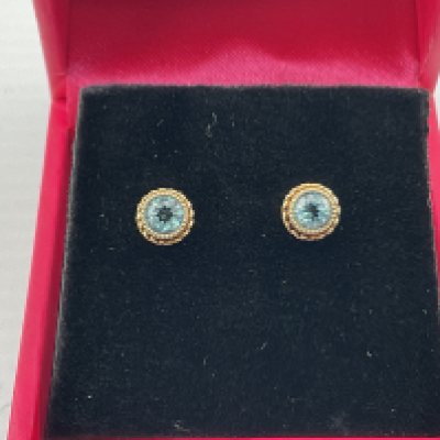 A pair of 9ct gold studs set with blue topaz. Postage category A.