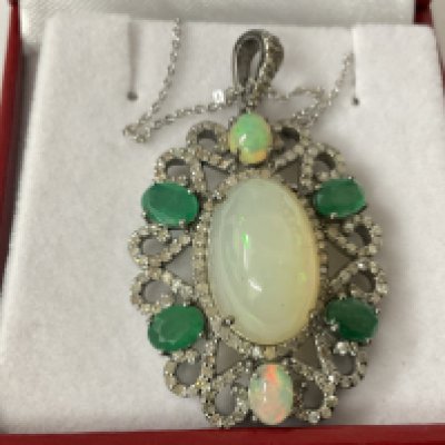 Silver floral style pendant set with opals, diamonds and emeralds on a silver chain, boxed. Opals 11.18ct. Emeralds 2.88ct. Diamonds 2.00ct. Postage category A.