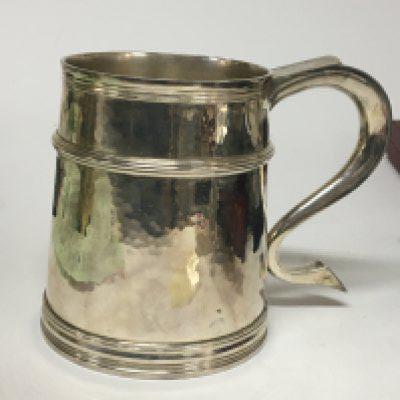 A Quality silver tankard of 18th century design with a shaped handle and hammered pattern sides with raised turning London hallmarks makers initials RC. Weight 580g no personal inscriptions and very good condition.