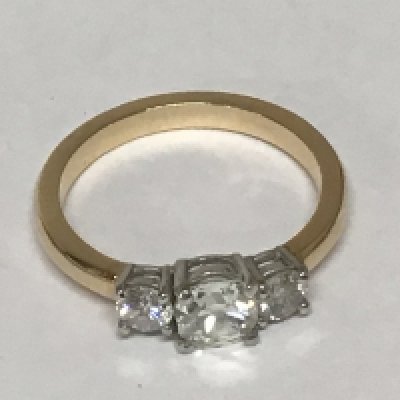An unmarked gold ring set with three cushion cut diamonds the central stone approximately 0.70 of a carat flanked by two further diamonds approximately 0.20 of a carat ring size P. Weight 4g.