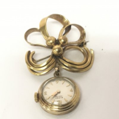 A gold cased ladies watch set on an open simulated ribbon gold plated brooch and a gold bar brooch. NO RESERVE