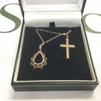 Two 9ct gold pendants on chains comprising a cross and one set with garnets. Shipping category A.