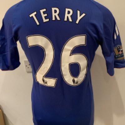 Chelsea 2010 - 2011 Match Worn Football Shirt: Blue short sleeve shirt with Gold Premier League Champions badges to sleeves. Terry 26 to rear. Worn v Tottenham on 12 December 2010.