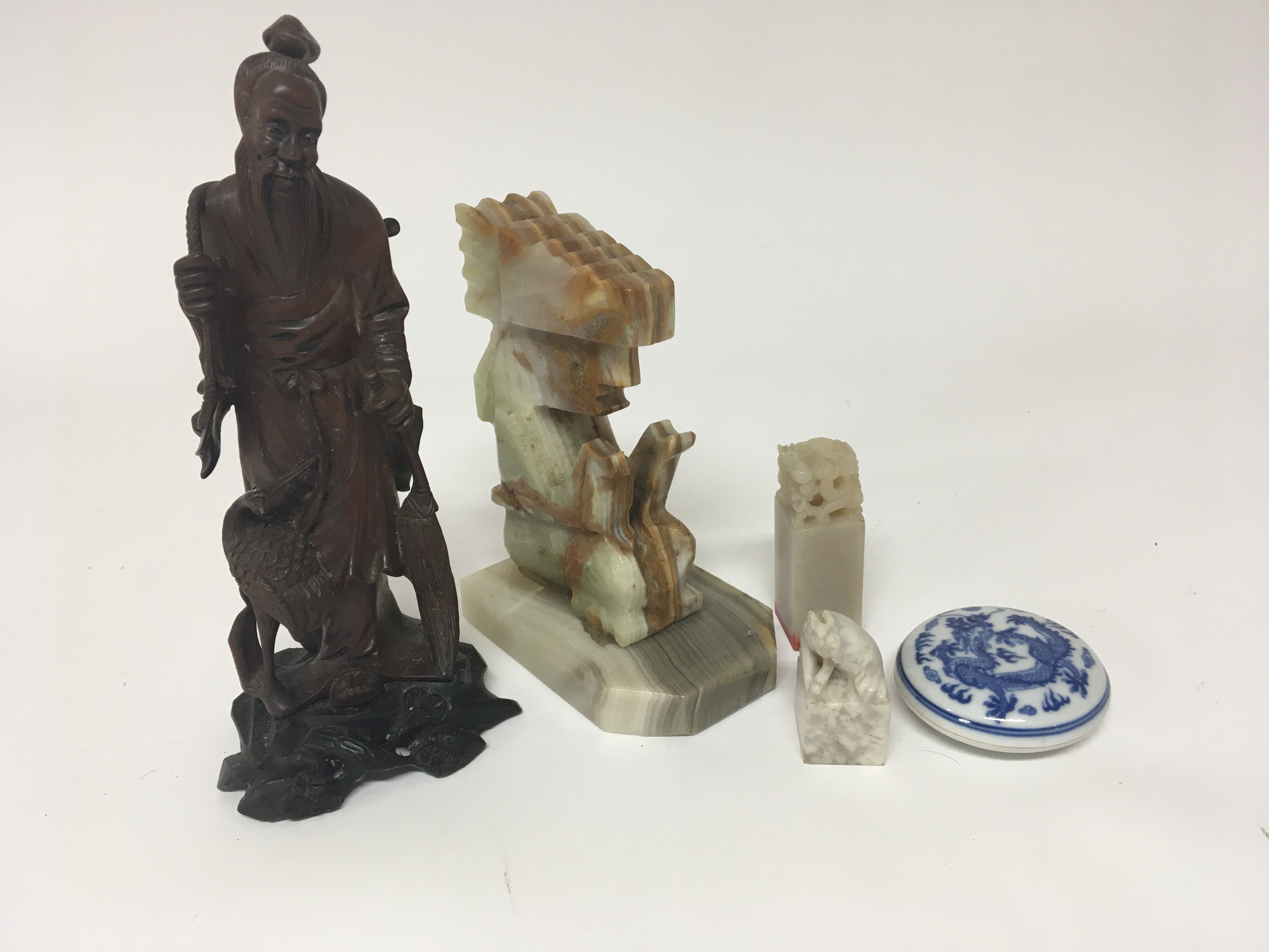 A carved hardwood Chinese figure of an elder seals and a 20th century Chinese red seal wax dish and cover and an onyx figure. (5)