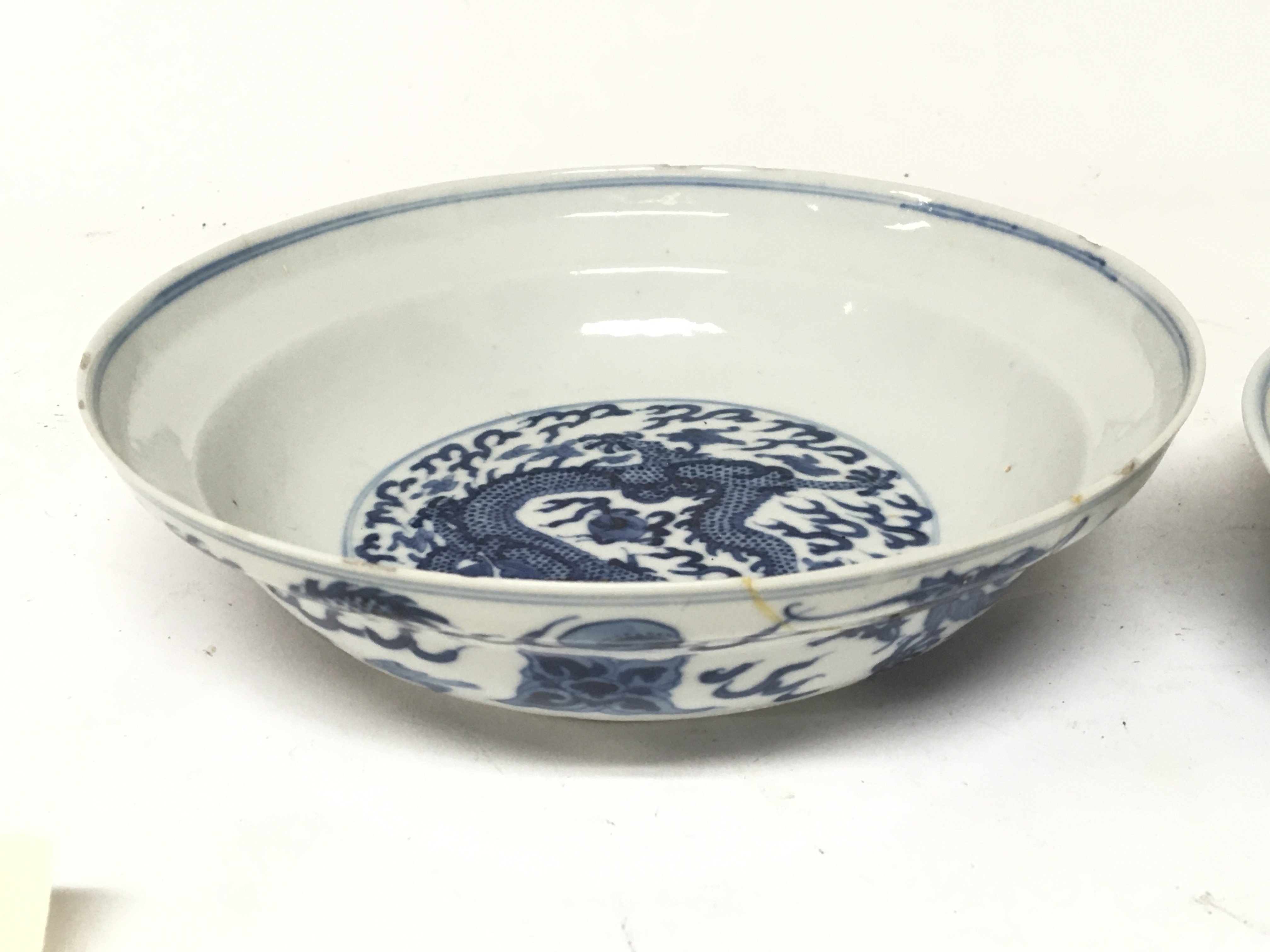 Two Chinese blue and white Export porcelain Mid to late Qing Dynasty dishes decorated with dragons chasing flaming pearls one with damage both with six caricature marks to the base. Larger dish 20cm diameter with damage see images smaller dish 18cm (2)