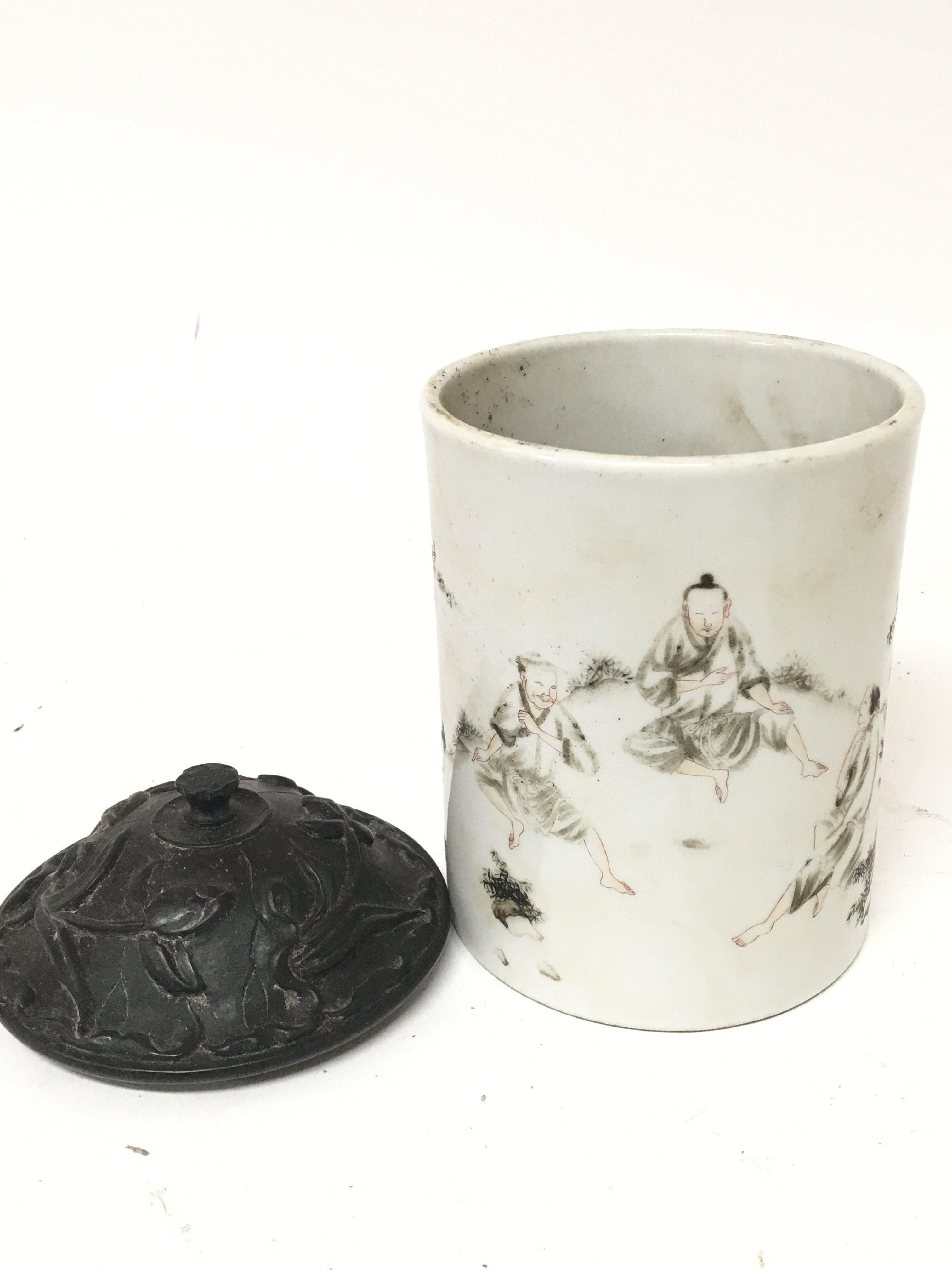An Early 19th century Chinese porcelain brush pot with a carved hardwood lid the sides painted with figures no obvious damage or restoration marks to the base. Height 13cm diameter 10cm