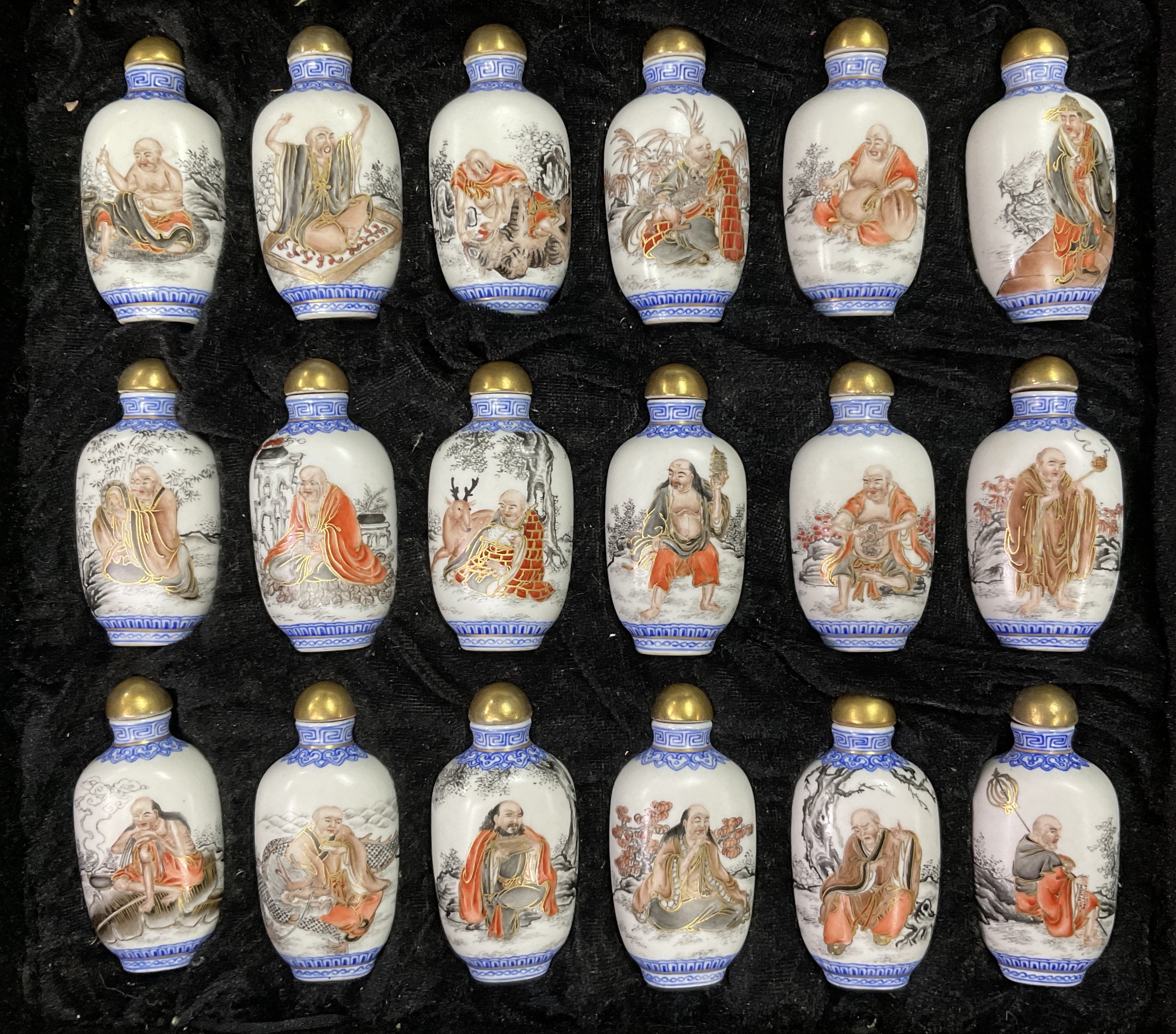 A cased set of 18 hand painted porcelain snuff bottles each with a different view of a Lohan, with gilt porcelain stoppers, 8cm including stopper.