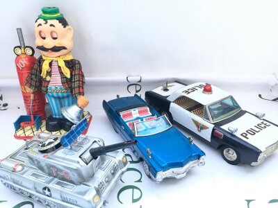 4 X Japanese Battery Operated Tinplate Toys. Including A Gino Neapolitan Balloon Blower (Boxed), A T-5 Tank, Police Car And A Cadillac. No Reserve. From A Lifetime Private Collection To Be Sold.