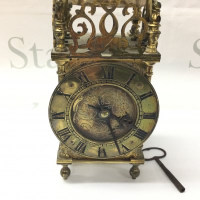 A brass lantern clock. Winds and runs. Approximately 21cm tall.