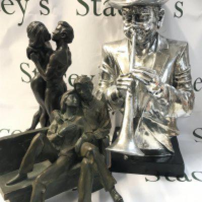 Figures including simulated bronze figure groups of lovers and a trumpet player figure. 26 to 46cm tall. This lot cannot be posted