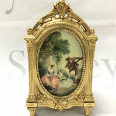 A French gilt trinket box with an oval plaque of classical figure design and embossed floral patterns. (damage to hinge at the door panel). Base marked Depose N.27. 8.5cm wide 15.5cm tall 7cm long. Postage category B