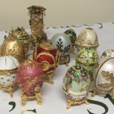 A collection of enamel and gilt metal elaborate egg caskets on small stands set with simulated Jewels and a conforming candle holder.