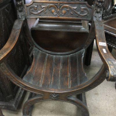 A oak carved open arm chair the solid seat on x framed stretchers .