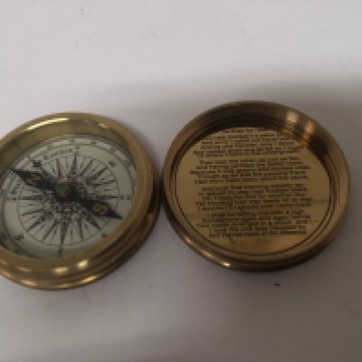 A brass pocket compass the inner case with poem by Robert Frost. The Road Not taken.