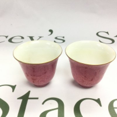 Two rice wine cups in a patterned red finish with a white interior, four character marks to base, approx height 5.5cm. Shipping category D.