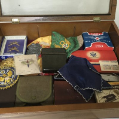 A Case containing American II world war and other items including embroidered silk sweetheart handkerchief badges pocket knifes and other oddments.