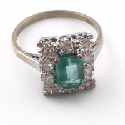 An 18k white gold ring set with central emerald surrounded by diamonds. Size P and 4.20g Postage B