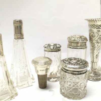 A collection of cut glass Perfume bottles with silver lids and collars , a silver vase , cork silver bottle stopper. This lot cannot be posted