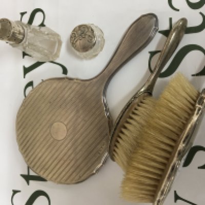A silver backed hand mirror two silver brushes and silver mounted cut glass bottle and small jar. (5)