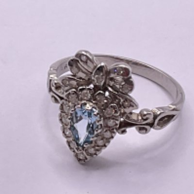 9ct white gold bow style ring set with pear shaped blue topaz and RBC diamonds. Topaz 0.30ct. Diamonds 0.20ct. Ring size approx N. Postage category A.